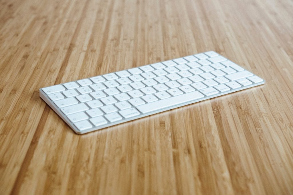 Photograph of a wireless keyboard on a wood surface.